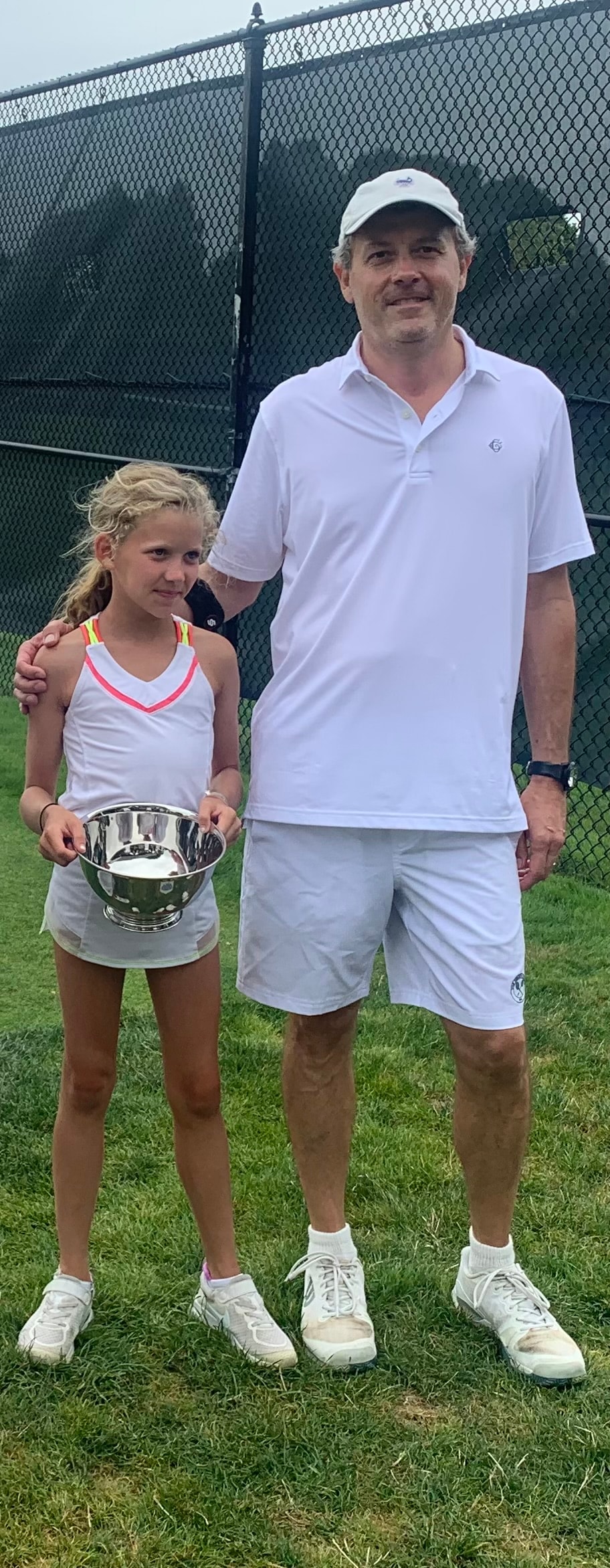 Eleanor holding a tournament trophy with her coach